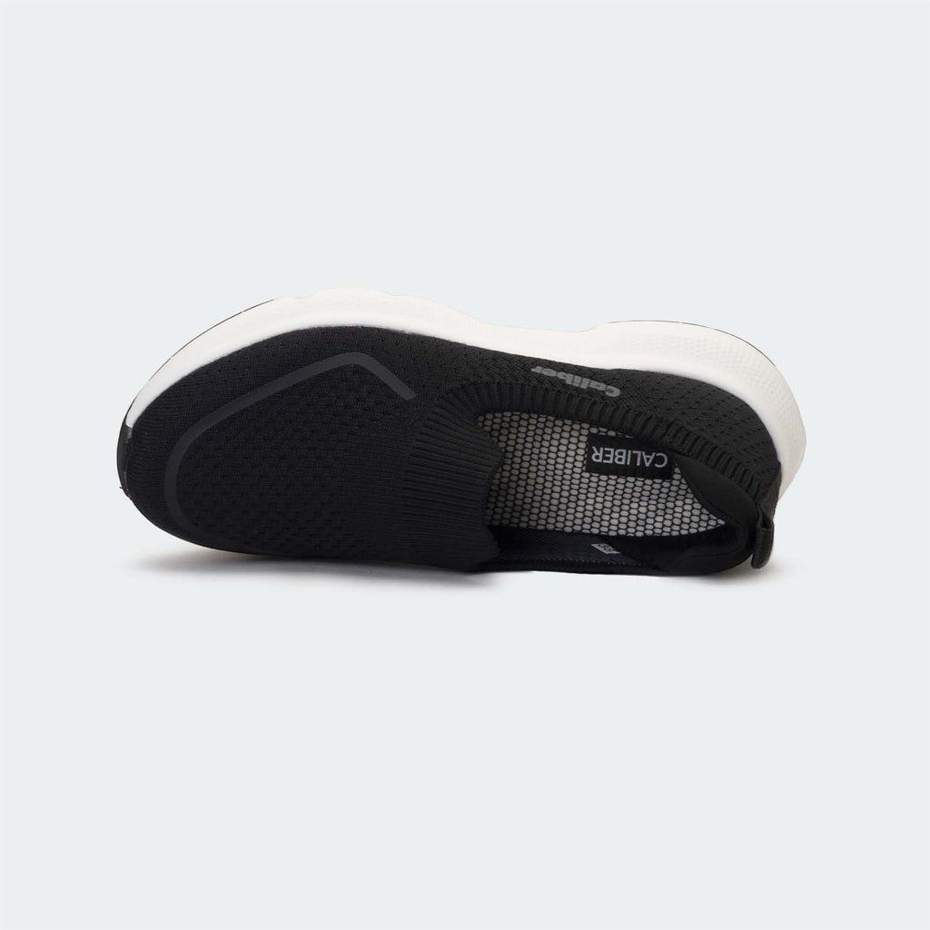 Caliber Shoes black knit slip-on sneakers with white EVA bubble sole and grey logo detail.