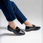 Black dress shoes worn with blue jeans on a light gray background, featuring the Caliber Shoes brand.
